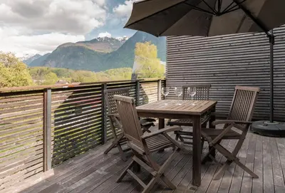 a wooden table and chairs on a deck with an umbrella at Apartment Panoramic Bovec in Bovec