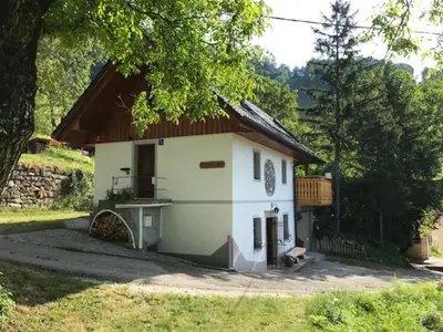 a small white house with a wooden roof at Počitniška hiša Mlekarna Grant in Grahovo