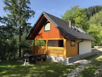 a small house with a picnic table in the yard at Počitniška hiša Mlekarna Grant in Grahovo