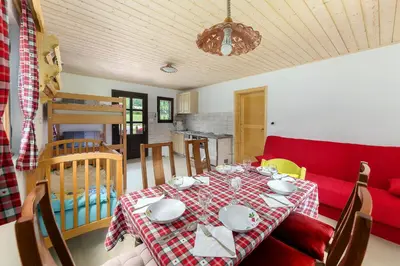 a dining room with a table and a red couch at Počitniška Hiša Voje in Srednja Vas v Bohinju