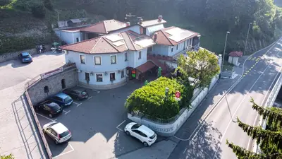 a large house with cars parked in a parking lot at Guest house Kočanija in Ilirska Bistrica
