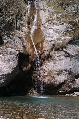 a waterfall on the side of a rocky cliff at Studio Brnat in Kobarid