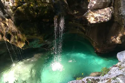 a pool of water in a cave with a waterfall at Studio Brnat in Kobarid