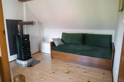 a green couch in a room with a wood stove at Country House Sveta Ana in Stari Trg pri Ložu