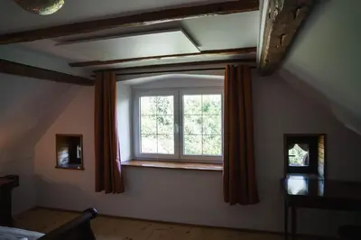 an attic room with a window with orange curtains at Country House Sveta Ana in Stari Trg pri Ložu