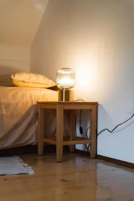 a table with a lamp on it next to a bed at Country House Sveta Ana in Stari Trg pri Ložu