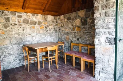 a wooden table and chairs in a stone room at Country House Sveta Ana in Stari Trg pri Ložu