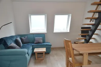 a living room with a blue couch and two windows at River Apartment in Bovec