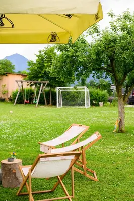 a yellow umbrella and a chair in a yard at GLAMPING HOUSE RANČ LUŽE in Luže