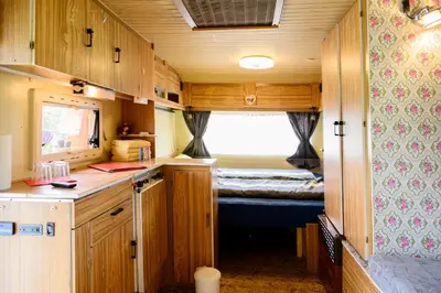 a kitchen with wooden cabinets and a room with a window at GLAMPING HOUSE RANČ LUŽE in Luže