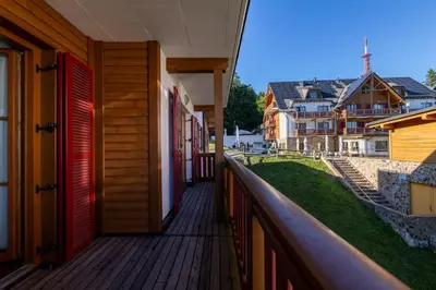 a balcony of a house with red doors and houses at Luxury apartments Prežin in Pohorje