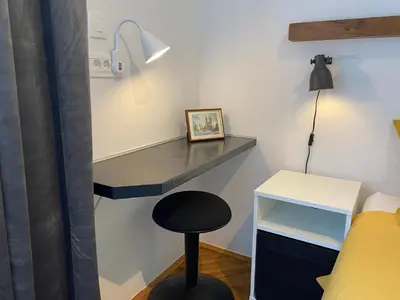 a room with a desk and a stool next to a bed at Boennium Apartments Green Oasis in Ljubljana