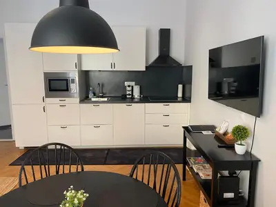 a kitchen with white cabinets and a black table and chairs at Boennium Apartments Green Oasis in Ljubljana