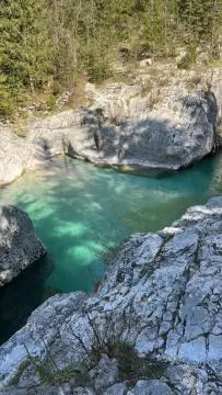a pool of green water between two large rocks at Roja House in Soča