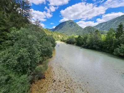 a river with trees and mountains in the background at Apartma Dora Bovec in Bovec