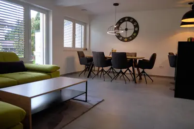 a living room with a table and chairs and a clock at Apartma La Casa in Radovljica