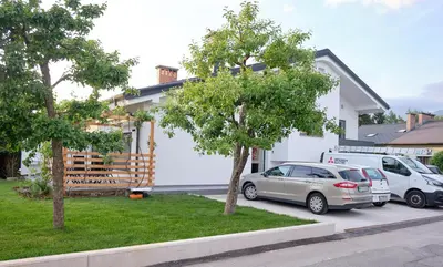 a house with two cars parked in a parking lot at Apartma La Casa in Radovljica