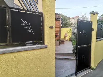 a yellow building with a black gate and a sidewalk at Apartma Qbed in Gračišče
