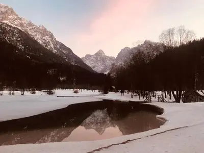 a pond in the snow with mountains in the background at Apartma Anton in Kranjska Gora