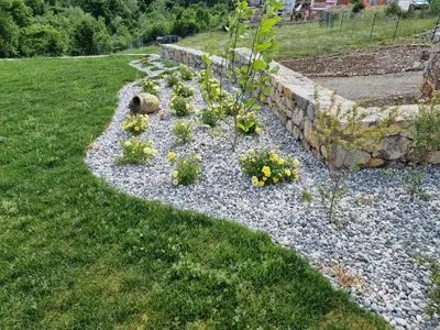 a garden with flowers and a stone wall at Shamarè Resort & Wellness Spa in Hrpelje