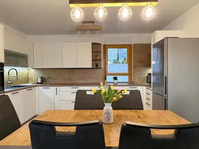 a kitchen with a wooden table with a vase of flowers at Apartma Ana in Manca in Begunje na Gorenjskem