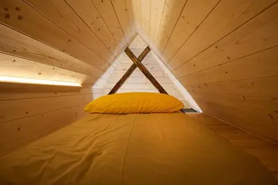 a bed in a small room with a wooden ceiling at NATUR BAJTA in Solčava