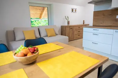 a kitchen and living room with a table with a bowl of fruit at Na-Ture Apartments in Zgornje Gorje