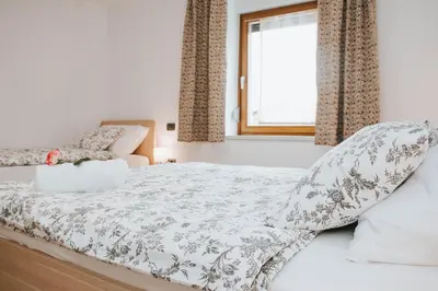 a bedroom with a white bed with a window at Apartmaji URŠIČ in Kobarid
