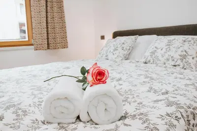 a bed with towels and a rose on it at Apartmaji URŠIČ in Kobarid