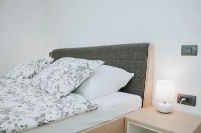 a bed with pillows and a lamp on a table at Apartmaji URŠIČ in Kobarid