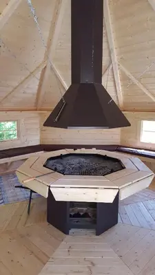 a stove in a wooden cabin with a hood at GUESTHOUSE Idila pod Nanosom in Senožeče