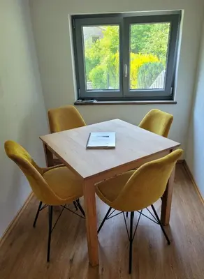 a wooden table with yellow chairs and a window at GUESTHOUSE Idila pod Nanosom in Senožeče