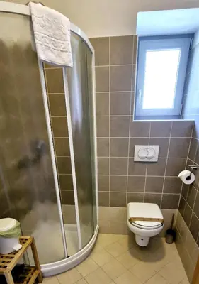 a bathroom with a shower and a toilet and a window at GUESTHOUSE Idila pod Nanosom in Senožeče