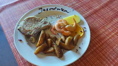 a plate of food with shrimp and toast on a table at Tičarjev Dom at Vrsic pass in Soča