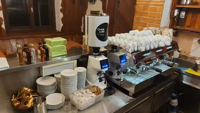a coffee machine with cups and plates on a counter at Tičarjev Dom at Vrsic pass in Soča