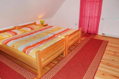 a large bed in a bedroom with a red rug at Eco tourist farm Mikl in Prevalje