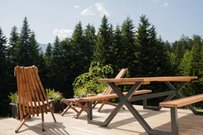 two chairs and a wooden bench on a deck at Hiša Breza in Mozirje