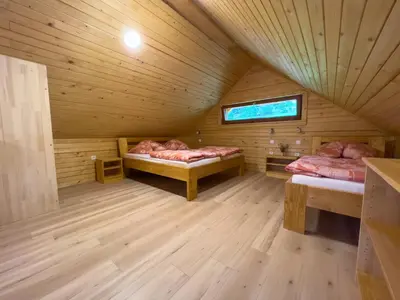 a room with two beds in a wooden cabin at Hiša Breza in Mozirje