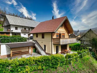 a wooden house with a balcony on a hill at Apartment Mari in Bohinj