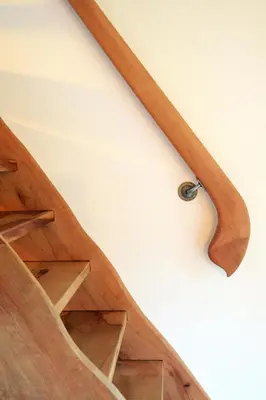 a close up of a wooden staircase with a metal rail at Granaries Pear & Walnut in Tolmin