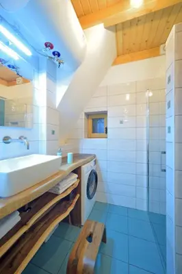 a bathroom with a sink and a washing machine at Granaries Pear & Walnut in Tolmin