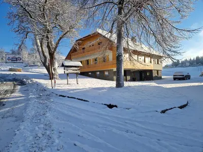 a building in the snow with a car parked in front at Turistična kmetija Ramšak in Zreče
