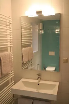 a white bathroom with a sink and a mirror at Apartments Cvetje v Jeseni in Škofja Loka