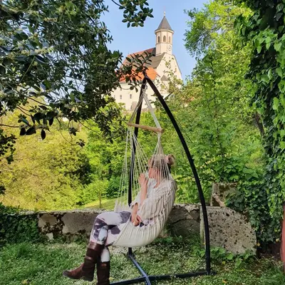 a woman sitting in a swing in a yard at Hiška pri Tisi in Ptujska Gora