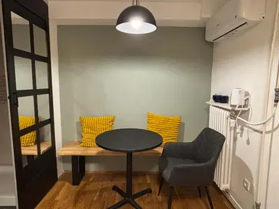 a room with a table and a chair and yellow pillows at DEKO-rooms in Ljubljana