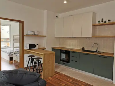 a kitchen with white cabinets and a kitchen with stools at Apartma Valan in Bovec