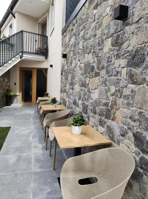 a row of tables and chairs against a stone wall at Boutique rooms by Petrič winery in Dobravlje