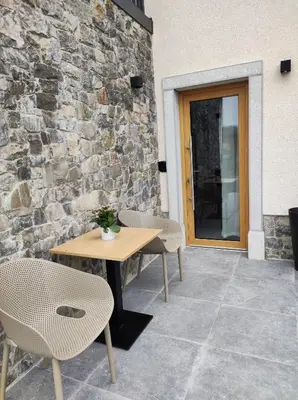 a patio with two tables and chairs and a stone wall at Boutique rooms by Petrič winery in Dobravlje