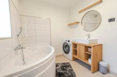 a bathroom with a tub and a sink and a washing machine at Holiday Home Lukc with free parking in Kobarid