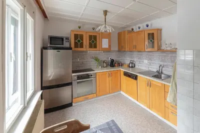 a kitchen with wooden cabinets and a stainless steel refrigerator at Vrtnarjeva hiša, The Gardener's Cottage in Radovljica